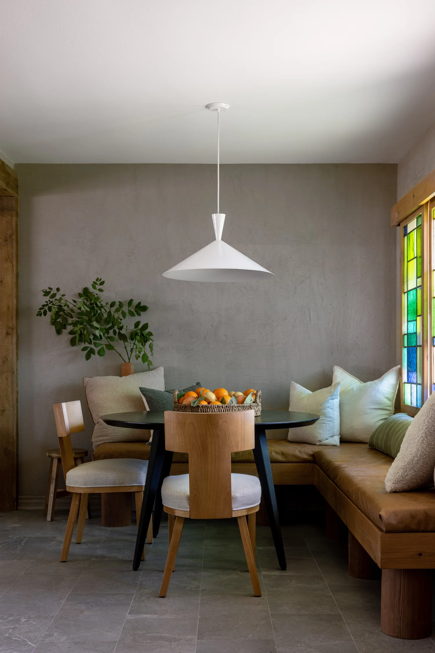 BBG interior: dining nook with a white pendant light, round table, and built-in banquette