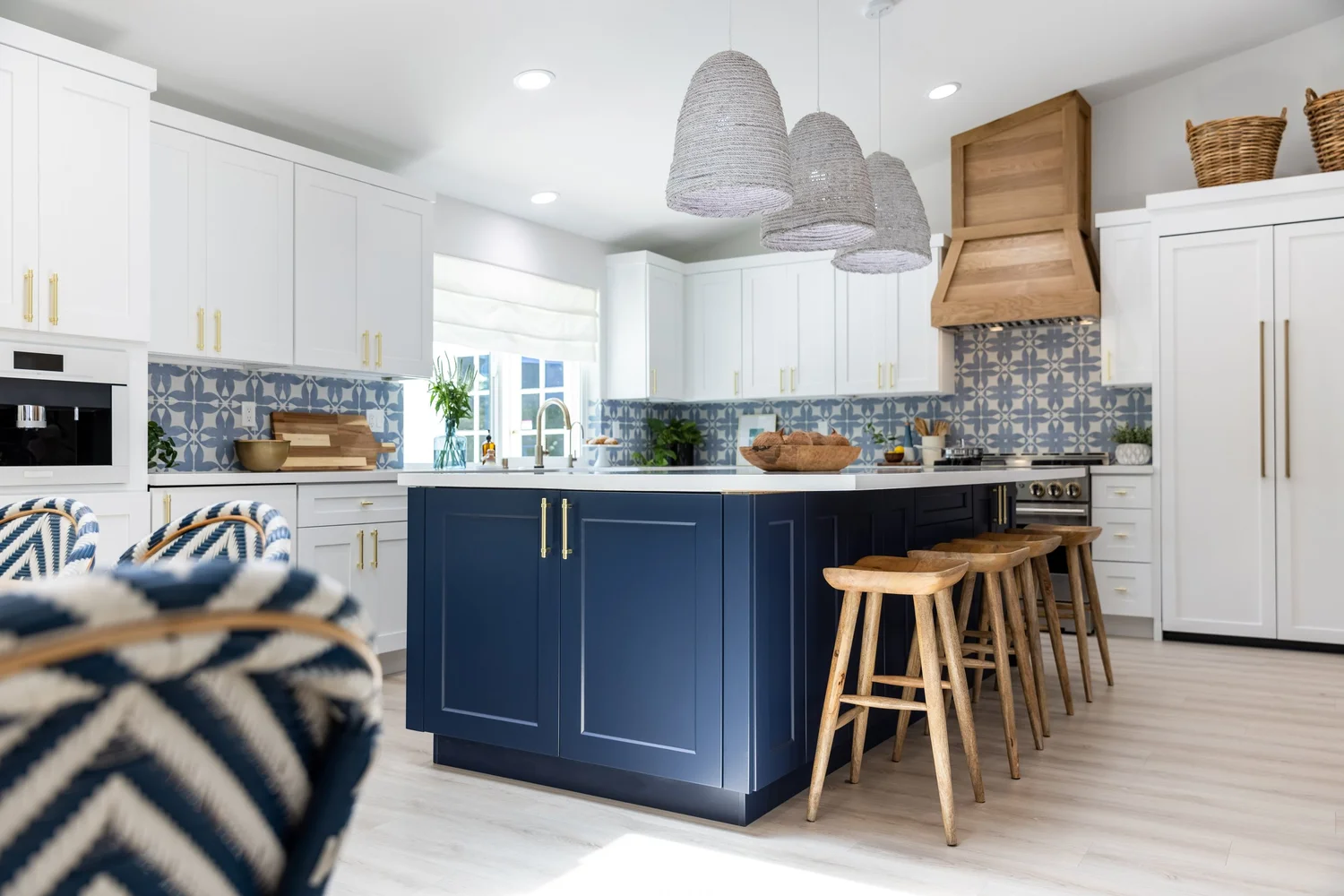 BBG interior: white kitchen with a navy island, wood stools, and blue patterned tile
